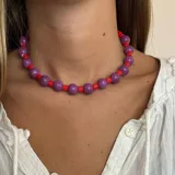 Collar corto de cuentas redondas grandes color violeta alternadas con cuentas tubulares pequeñas color rojo.