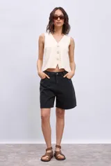 Chaleco de punto color crema con escote en V y cierre frontal con botones a tono.