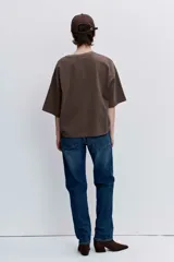 Remera blanca de corte oversize con cuello redondo y mangas cortas, presenta un pequeño bordado de cerezas en el pecho.