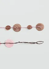Collar largo de diseño artesanal confeccionado con hilos de poliéster y apliques circulares de nácar en tonos rosados y marrones.