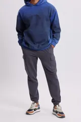 Pantalón estilo jogger en color gris oscuro, con diseño cargo que incluye bolsillos laterales amplios. Cuenta con cintura elástica con cordón ajustable y puños acanalados en los tobillos.