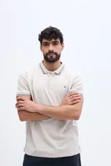 Chomba de piqué en color negro, de manga corta, con cuello y puños tejidos con líneas a contraste. Presenta cierre frontal parcial con botones y pequeño logo bordado en el pecho.