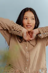 Camisa de lino blanca con detalles de encaje crochet en los puños y en el ruedo. Presenta un diseño romántico con cierre frontal de botones.