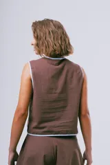 Top negro sin mangas de estilo chino, con ribetes marrones y cierre delantero de nudos tradicionale.