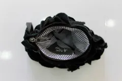 Cartera de mano verde oscuro hecha de círculos de lana merino afieltrada teñida artesanalmente, con asa de cuero marrón.