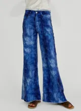 Pantalón de jean con diseño de lavado tipo acuarela en tonos azules, de corte recto y holgado con ruedo desflecado.