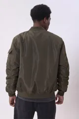 Campera bomber color verde militar con cierre frontal, bolsillos laterales con solapa y bolsillo en la manga izquierda.
