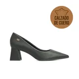 Zapato de vestir de cuero negro con punta fina y taco cuadrado de altura media. Presenta un detalle de aplique metálico dorado con el logo de la marca en el lateral.