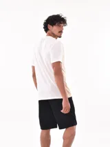 Remera de corte oversize, con diseño bicolor que combina blanco y beige. Presenta un bolsillo frontal en el pecho con el logo de la marca bordado y una etiqueta pequeña en el ruedo.