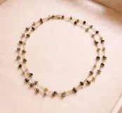 Collar largo de cadena fina dorada con pequeñas piedras naturales engarzadas a lo largo de toda la pieza.