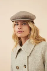 Boina con visera de lana fina uruguaya natural, sin teñir, con diseño de tejido texturizado en tonos beige y marrón.