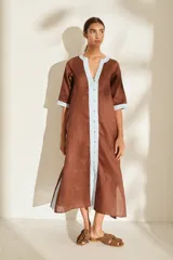 Túnica midi de lino color marrón con detalles en celeste claro en la tapeta de botones, el cuello y los puños, de manga media y corte recto.