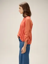 Remera de manga larga color blanco con cuello redondo y detalles fruncidos con lazos en las mangas.