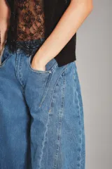 Jean de corte wide leg en color azul medio, con costuras verticales decorativas a lo largo de las piernas y diseño de tiro medio.