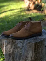 Botines Chukka de cuero marrón con cordones y suela de goma negra.