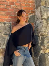 Capa asimétrica de lino, color negro, con diseño más corto en el frente y largo en la parte posterior, de silueta amplia y caída fluida.