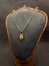 Dije en forma de escarabajo con acabado dorado envejecido, decorado con incrustaciones de cristales brillantes en la cabeza y el centro del cuerpo.