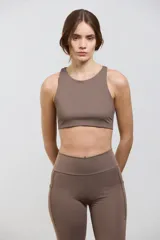 Top deportivo de compresión media con escote redondo, diseño al cuerpo y espalda abierta. Cuenta con elástico interno en la cintura para mayor sujeción.