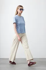 Remera de manga corta y cuello redondo, confeccionada en algodón. Presenta costuras verticales visibles en el frente que generan un efecto de entalle y estructura en la cintura.