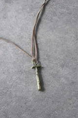 Collar de tiento de cuero marrón con dije en forma de letra y placa metálica con la inscripción de la marca.