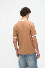 Remera de manga corta azul con cuello redondo, puños y bandas en los hombros en color tostado. Presenta un pequeño bordado rojo en el pecho y está confeccionada en suave jersey de algodón con calce clásico.
