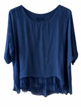 Blusa azul marino de corte amplio y vaporoso, con escote redondo y mangas cortas. Presenta un diseño de doble capa en el bajo con terminación desmechada.