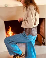 Cinturón ancho de cuero marrón oscuro con borde festoneado y cordones cruzados en la parte superior.