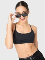 Top deportivo de bajo impacto color negro, con escote redondo y tirantes finos ajustables que se cruzan en la espalda. Cuenta con almohadillas removibles.