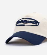 Gorra de béisbol con diseño bicolor, cuerpo en color crema y visera en azul marino. Presenta un bordado frontal con lettering en relieve color azul.