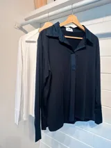 Chomba de manga larga con cuello polo y cierre frontal parcial, confeccionada en algodón liso con puños ajustados.