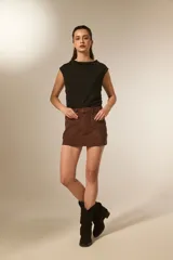 Minifalda negra de poliéster con corte al cuerpo, tiro alto y detalle de tachas doradas decorativas a lo largo de la costura lateral y el bolsillo delantero.