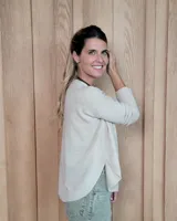 Sweater de punto color beige, con cuello en V, manga larga con puños acanalados y diseño holgado.