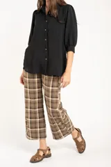 Blusa de corte oversize en color blanco, con cuello camisero, cierre frontal de botones y mangas tres cuartos con sutiles frunces en los hombros.
