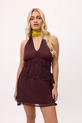 Vestido corto color borgoña, con escote halter, tiras finas y detalle de lazos en la cintura.