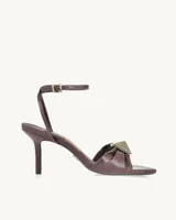 Sandalias de cuero color borgoña con taco fino y pulsera al tobillo. Presentan un aplique metálico dorado en forma de cuadrado en la parte delantera.