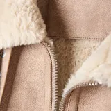 Campera de estilo aviador en color taupe, confeccionada en material símil gamuzado con interior y detalles de bordes en corderito sintético color crema. Presenta cierre frontal, dos bolsillos frontales con solapa y botones metálicos, y cuello solapa.