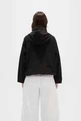 Campera corta de nylon en color negro, con cuello alto, capucha integrada y cierre frontal oculto con solapa.