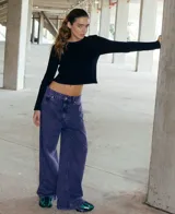 Jean de corte oversized y tiro medio-alto, confeccionado en denim de color violeta con diseño de cinco bolsillos y cierre frontal con botón y cremallera.