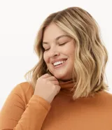 Blusa de manga larga color ocre, con cuello alto y corte ajustado.