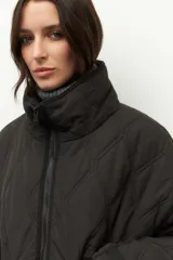 Campera corta color marrón con diseño capitoneado de rombos, cuello alto y bolsillos frontales grandes.