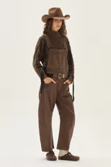 Overol de jean color marrón con calce barrel, tiro medio, pierna ancha y redondeada que termina a la altura del tobillo.