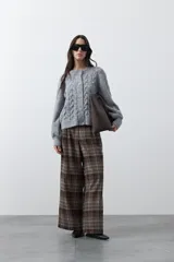Cardigan de tejido de punto color marrón chocolate, con diseño de trenzas en el frente y mangas. Presenta cuello redondo, cierre frontal con botones al tono y puños acanalados.