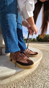 Zapatillas de cuero color marrón con detalles texturizados, cordones al tono y suela de goma.