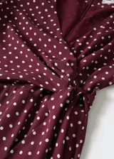 Mono largo de tejido fluido con estampado de lunares. Presenta cuello en pico, mangas largas acampanadas y un nudo ajustable en la cintura que entalla la silueta. Incluye forro interior.