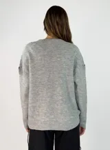 Sweater de punto gris con cuello en V, manga larga y detalles de costuras decorativas en color negro a lo largo del centro y en las mangas.