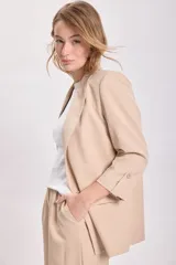 Blazer de color visón con mangas tres cuartos, solapas clásicas y cierre frontal con un botón. Presenta bolsillos laterales con solapa.