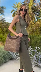 Cartera tipo bandolera de gran tamaño, confeccionada en cuero sintético con acabado desgastado. Cuenta con una asa corta fija, una correa larga regulable y extraíble, y una placa metálica con la marca en la parte frontal.