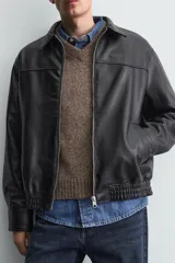Cazadora bomber de efecto piel color marrón oscuro, con cuello solapa, cierre frontal de cremallera, bolsillos de vivo en cadera y bajo elástico.