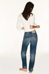 Jeans de tiro medio con corte straight, color azul con efecto lavado y roturas sutiles, cinco bolsillos y cierre frontal con cremallera y botón metálico.