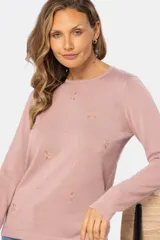 Buzo de tejido de punto fino en color rosado, con cuello redondo y mangas largas. Presenta un delicado bordado de pequeñas flores dispersas por toda la prenda.